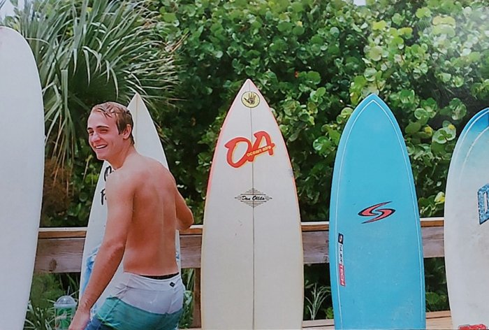 Отсканированное изображение серфера, позирующего перед досками для серфинга