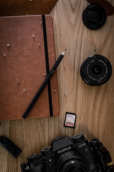 Объективы Fujifilm и фотоаппарат с блокнотом и карандашом на деревянном столе