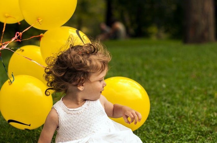 детская фотография в откровенном кадре с зеленым полем и желтыми воздушными шарами