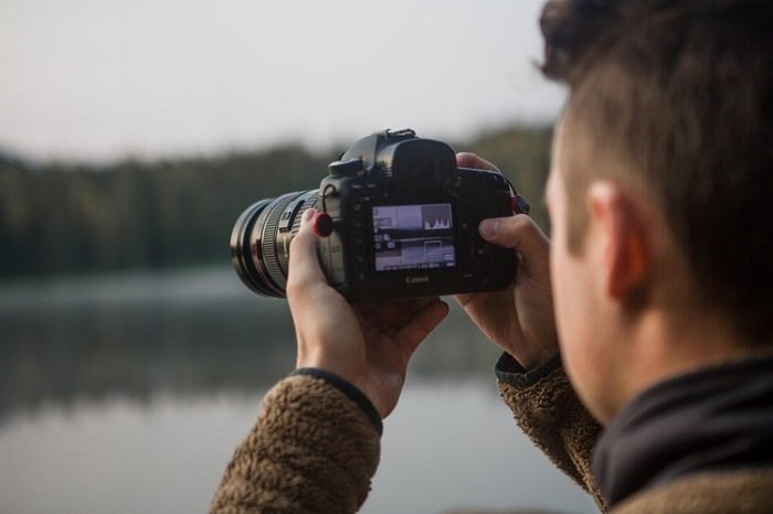 фотограф делает снимок на фоне размытого озера