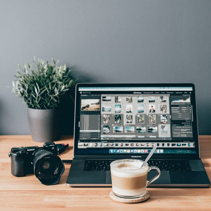 ноутбук, показывающий фотографии, загруженные с камеры за чашкой кофе