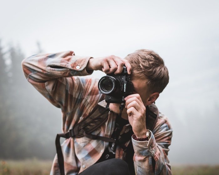 Мужчина фотографируется на улице с камерой Fujifilm и объективом