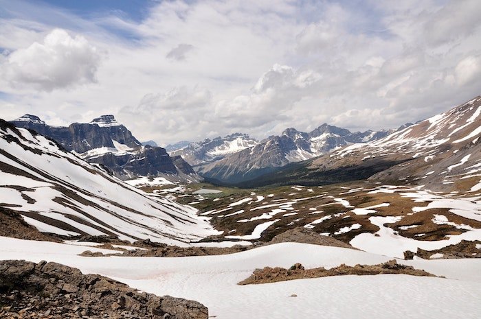 Пейзажная фотография гор, облаков, голубого неба и скалистой бесплодной земли со снегом