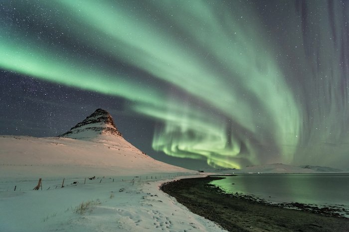 aurora borealis photographed shining over a snowy landscape