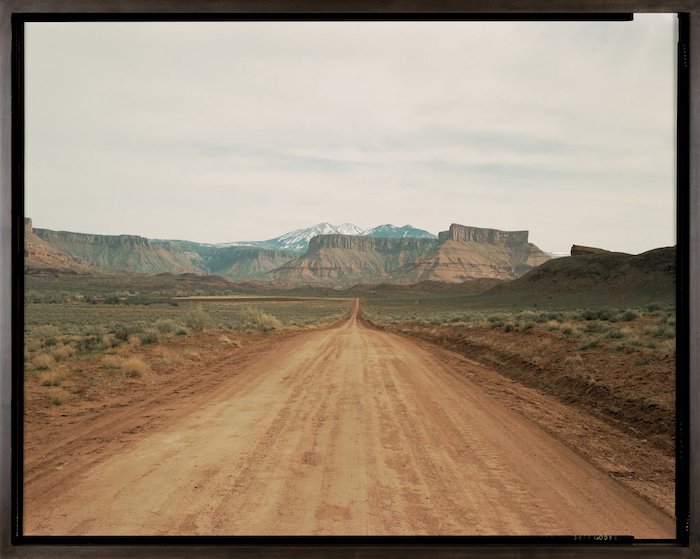 пейзаж пустыни: одинокая грунтовая дорога, ведущая к скалистой гряде