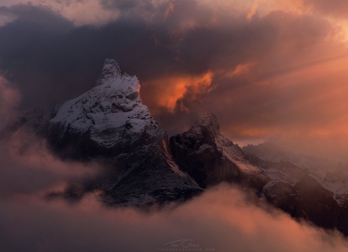 драматическая пейзажная фотография: туман и облака окружают заснеженную вершину