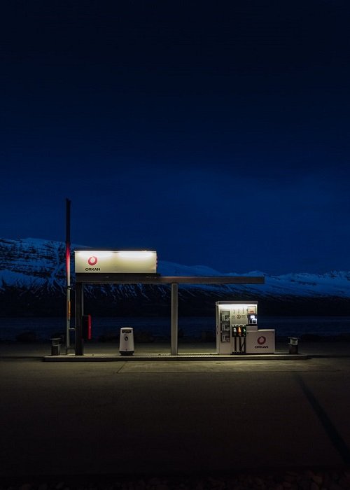 изображение бензоколонки, снятое при слабом освещении с темным пейзажем на заднем плане