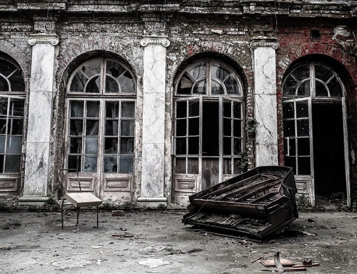 разрушенный рояль перед разбитыми арочными окнами