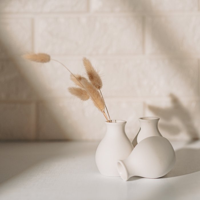 Lifestyle photo of small, white vases with wheat