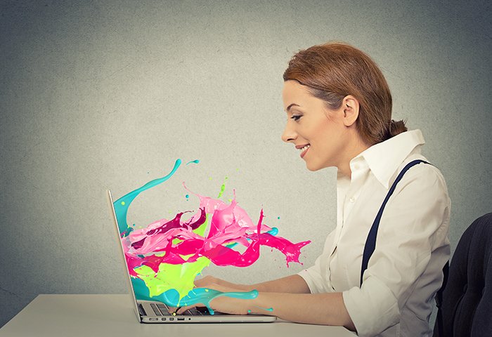 Боковой вид профиль привлекательный счастливый молодой деловой женщины работает на ноутбуке компьютер красочные брызги выходя из экрана эффект жидкости изолированные серый фон стены. Positive face expression vision