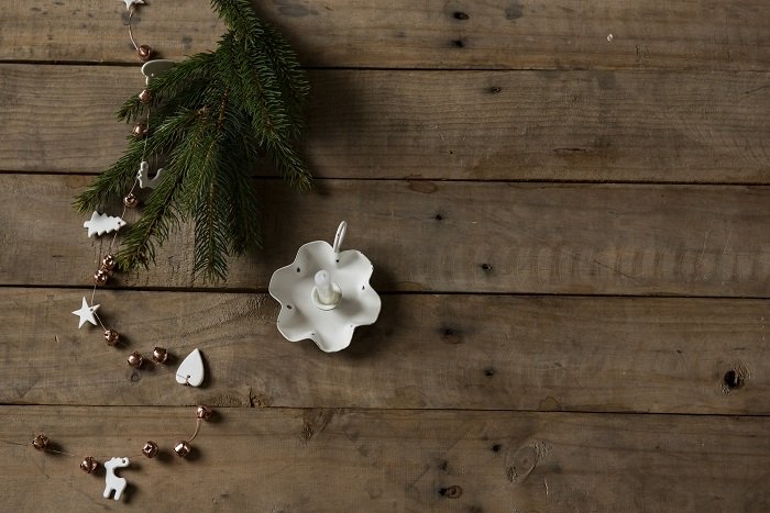 flat lay background idea: unlit candle and pine needles against wooden background