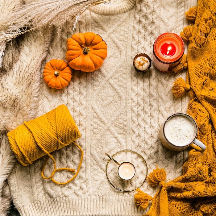 flat lay background idea: pumpkin, hot chocolate, and a candle on top of the autumn sweater