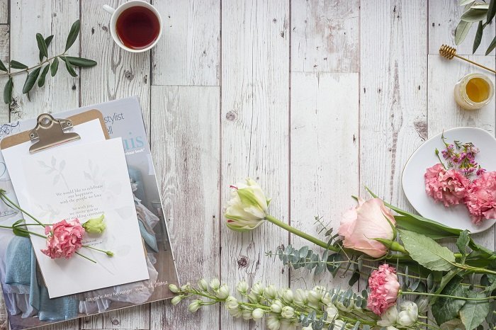 flat lay background idea: flowers and an invitation against faux wood backdrop