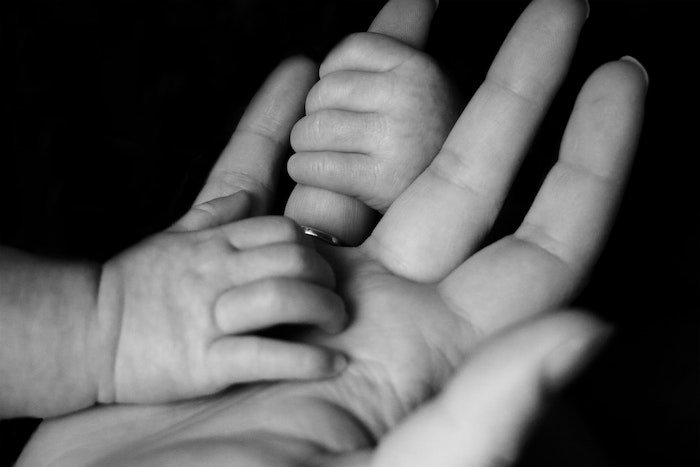 Пример фотографии поколения: одна рука ребенка держит безымянный палец родителя, а другая рука ребенка лежит на ладони