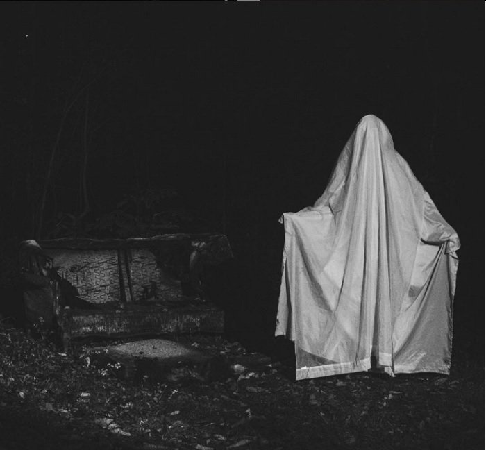 идея фотографии ужасов: человек с накинутой на него белой простыней в темной и жуткой обстановке