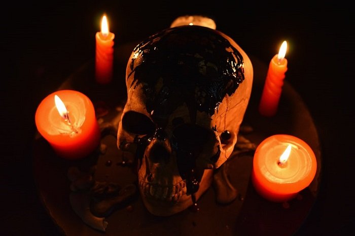идея фотографии ужасов: покрытый кровью череп в окружении 5 оранжевых свечей