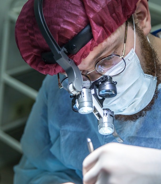 Медицинская фотография: Крупный план врача в хирургической лупе, проводящего операцию