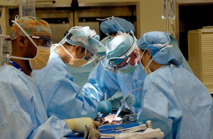 Медицинская фотография: Хирурги в синих халатах и масках делают операцию в операционной