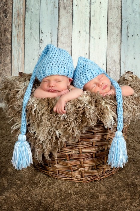 новорожденные близнецы фото идеи: новорожденные близнецы в голубых вязаных шапочках спят в мягкой плетеной корзине