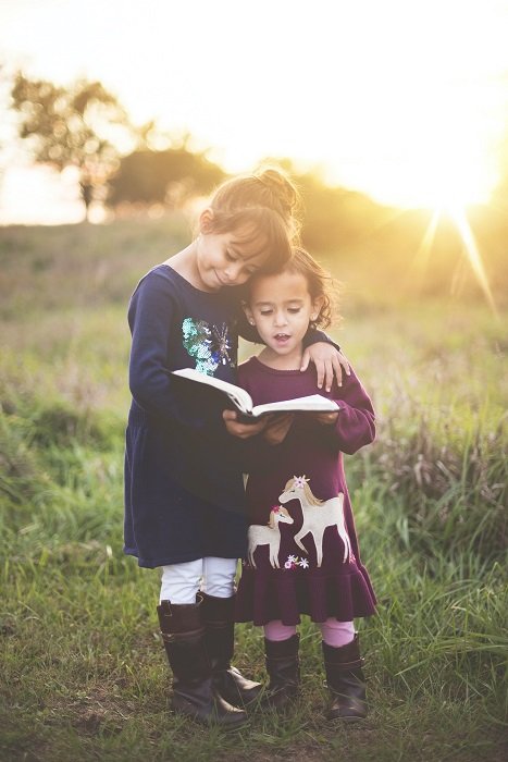 фото идеи для братьев и сестер: сестры обнимаются, читая книгу