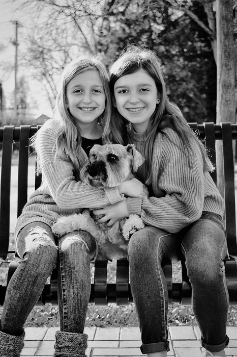 фото идеи для братьев и сестер: сестры сидят на скамейке со своей собакой