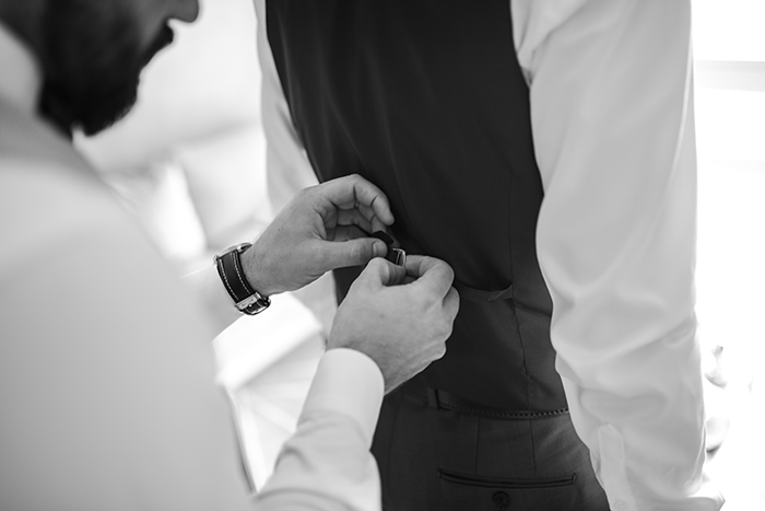 groomsmen getting ready: a black and white photo of a groomman adjusting a waistcoat