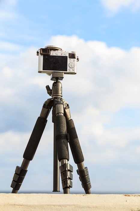 камера на мини-штативе перед большим голубым небом