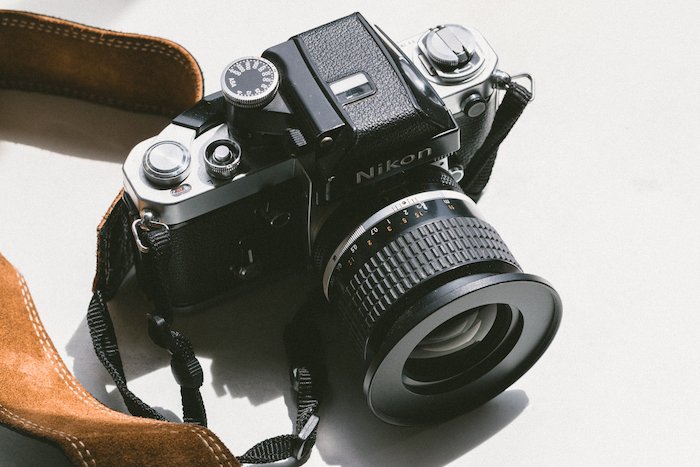 винтажная пленочная камера Nikon с коричневым кожаным ремешком с аббревиатурами объектива