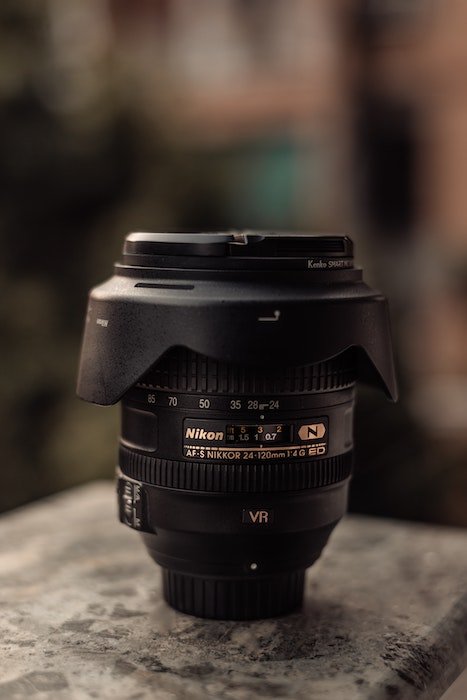 вертикальный объектив Nikon с крышкой и блендой, на которой видны аббревиатуры объектива