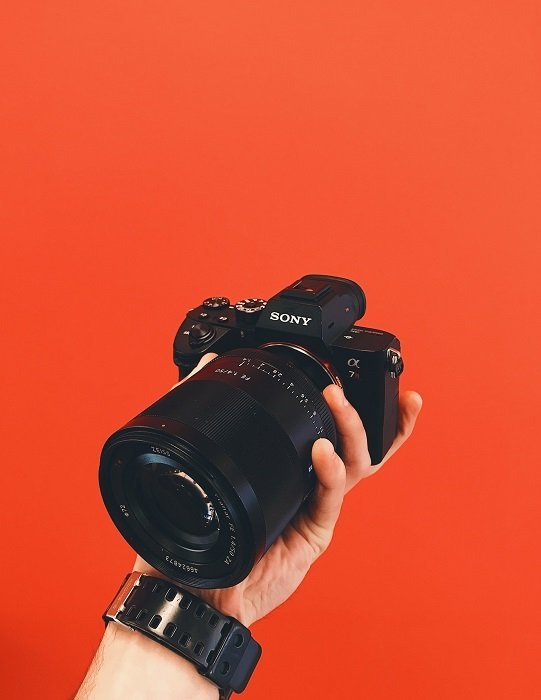 Sony a7 в руке фотографа на красном фоне