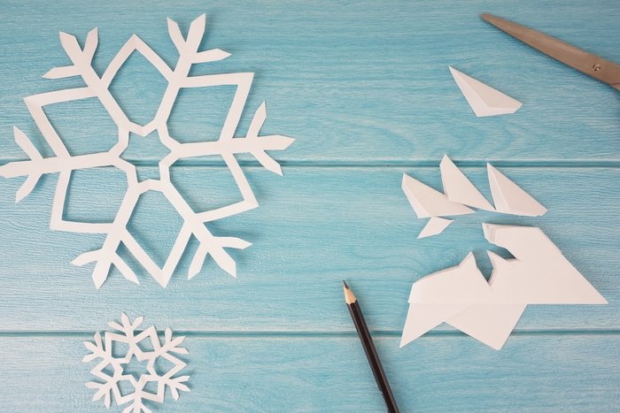 Christmas flat lay of cut out snowflakes pencil and scissors