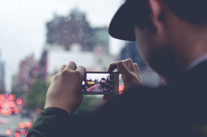 фотограф использует свой смартфон для съемки городского пейзажа