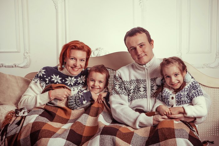 Семья под одеялом и в шерстяных свитерах для рождественской открытки фото идеи