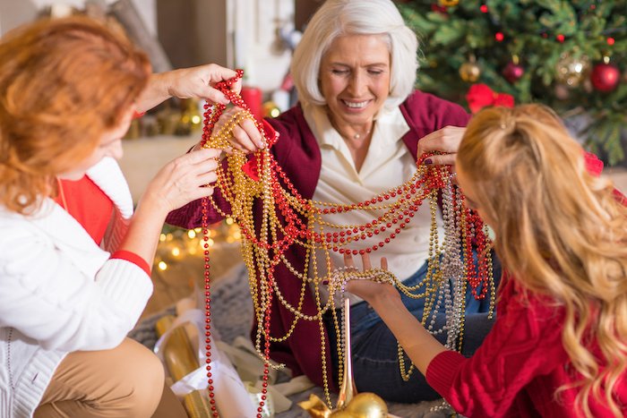 Члены семьи распутывают елочные украшения для новогодней открытки фото идеи