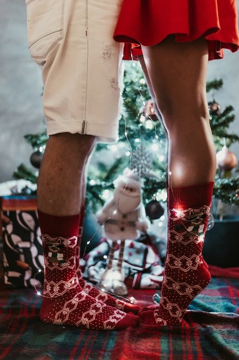 Вдохновение для рождественской фотосессии: женская половина этой пары стоит на носочках, чтобы поцеловать своего парня