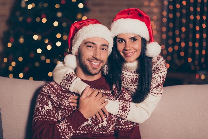 портрет пары в рождественских свитерах и шапках Санты