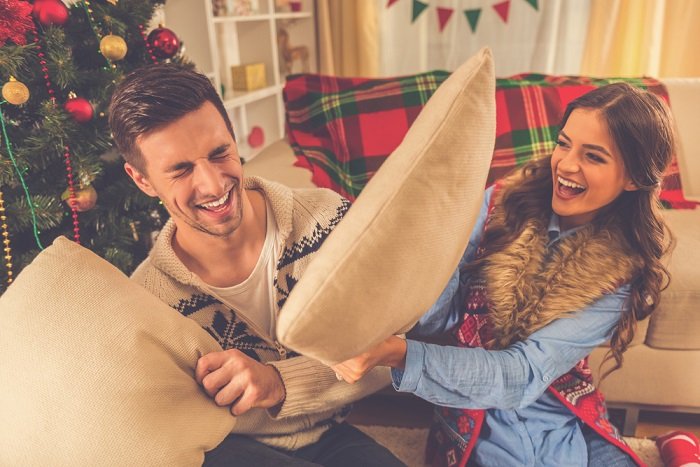 Идеи фотосессии рождественской пары: пара наслаждается смехом во время боя подушками