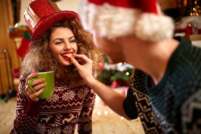 рождественские идеи фотосессии пары: мужчина кормит свою девушку печеньем