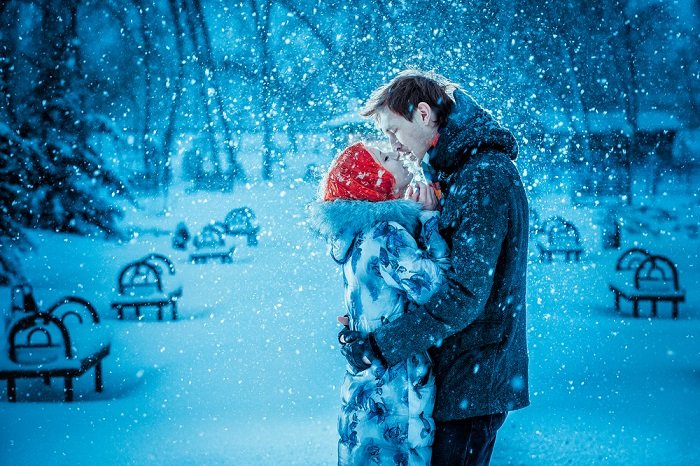 Вдохновение для рождественской фотосессии: пара целуется, пока вокруг них падает снег