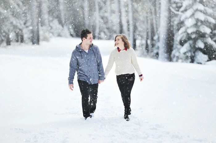 Советы для рождественской фотосессии пары: пара идет рука об руку по снегу