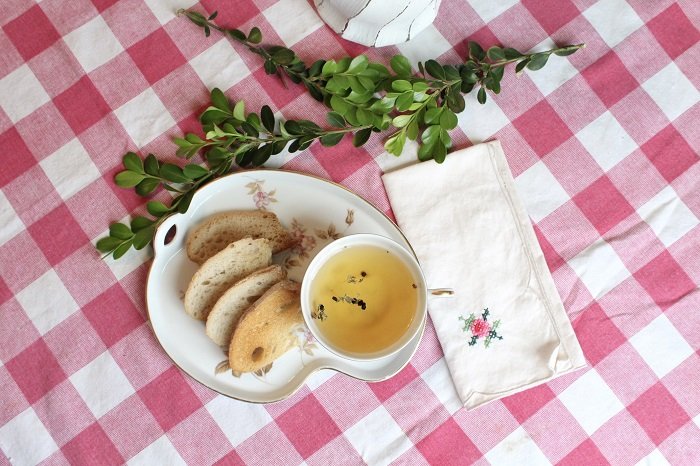 Tea in cup and bread on the plate on top of the gingham food photography prop tablecloth