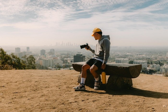 фотограф сидит на скамейке с видом на горизонт города