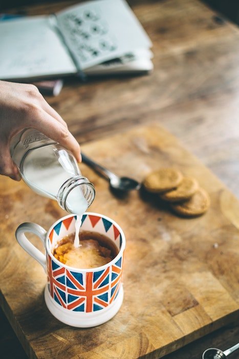 Молоко наливают в кофейную кружку с флагом Великобритании, используемую в качестве реквизита для фуд-фотографии