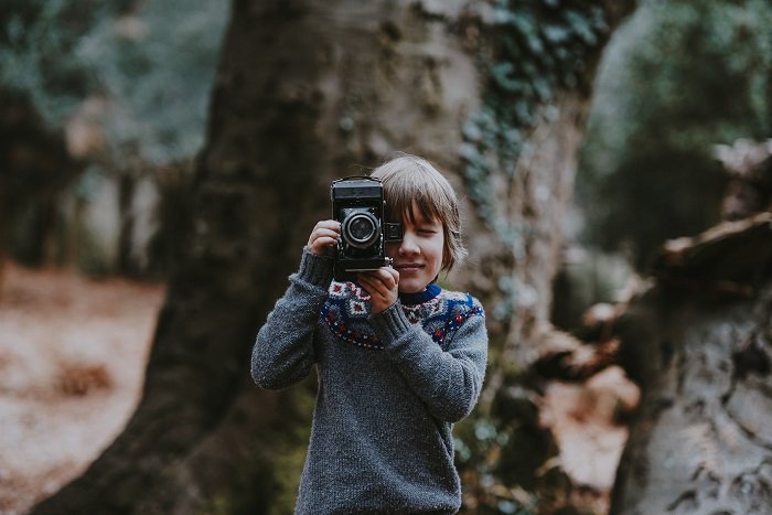 маленький мальчик фотографируется в лесу