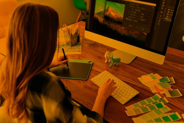 Женщина работает с планшетом и настольным компьютером, редактируя фотографии