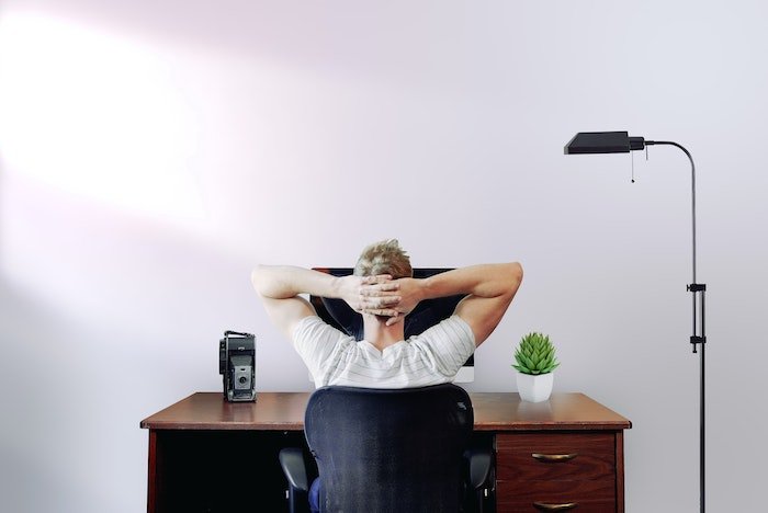 Мужчина отдыхает перед компьютером с винтажной камерой на столе
