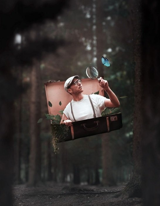 Идея фотоманипуляции человека с лупой, выходящего из чемодана в лесу