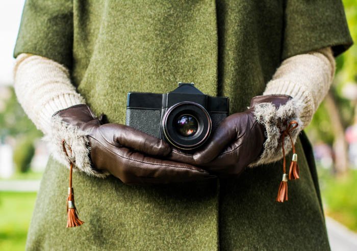Руки в кожаных фотоперчатках держат камеру