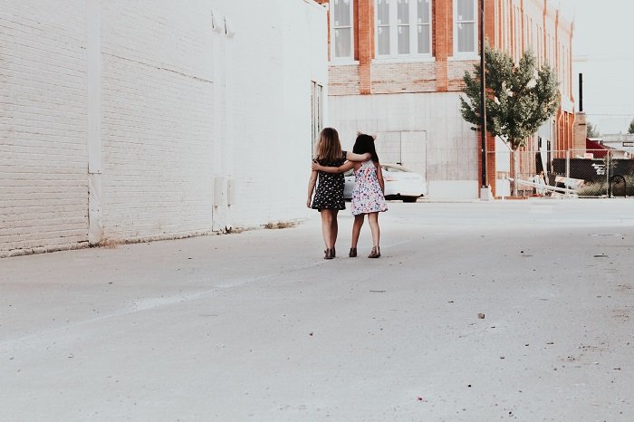 две молодые девушки идут под руку по аллее как идея сестринской фотосессии