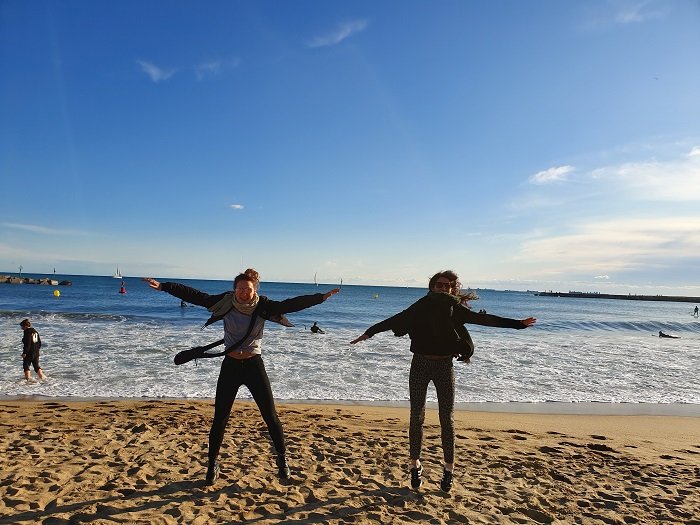 two girls doing star jumps on the beach a sisters photoshoot idea